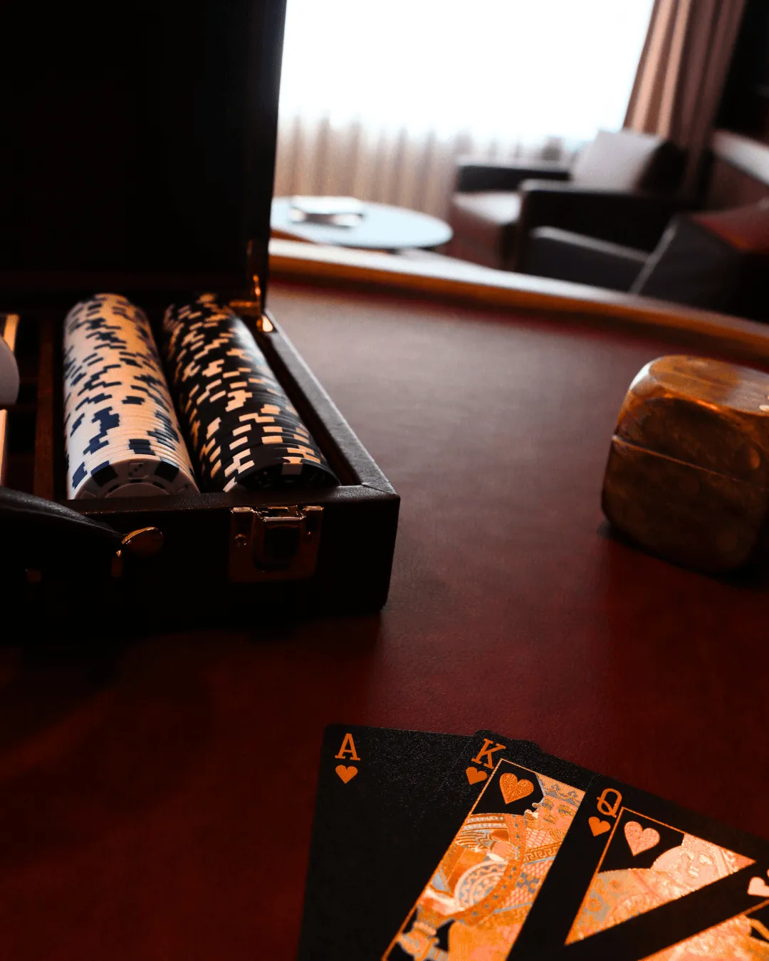 Eine offene Hülle mit Pokerchips, Spielkarten auf einem Tisch und ein unscharfer Hintergrund mit Sofas
